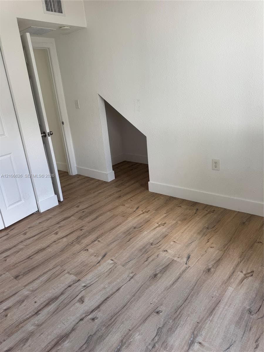Wood-finish flooring, recessed alcove, and six-panel interior door