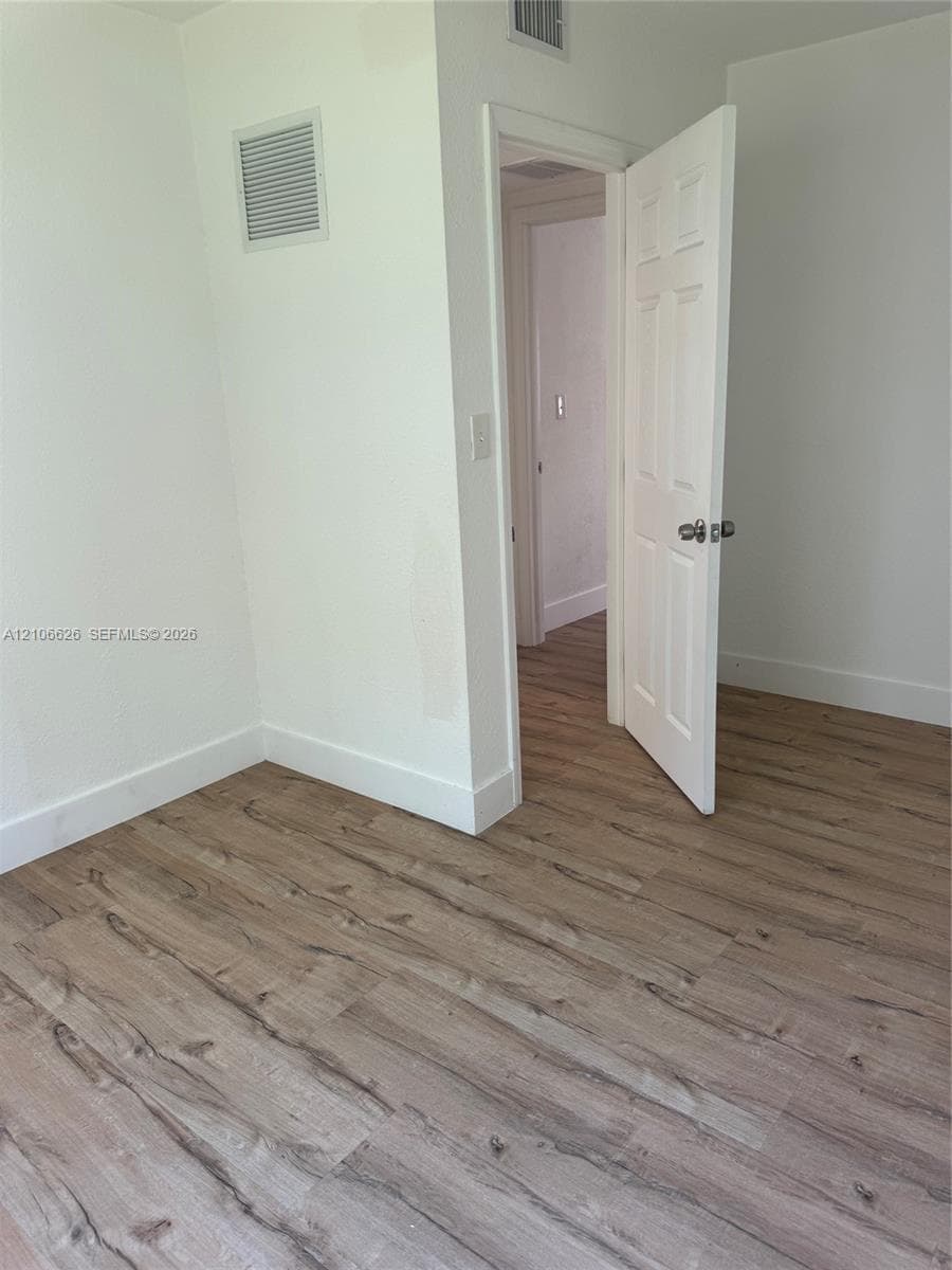Neutral wall color, wood-finish flooring, and six-panel interior door