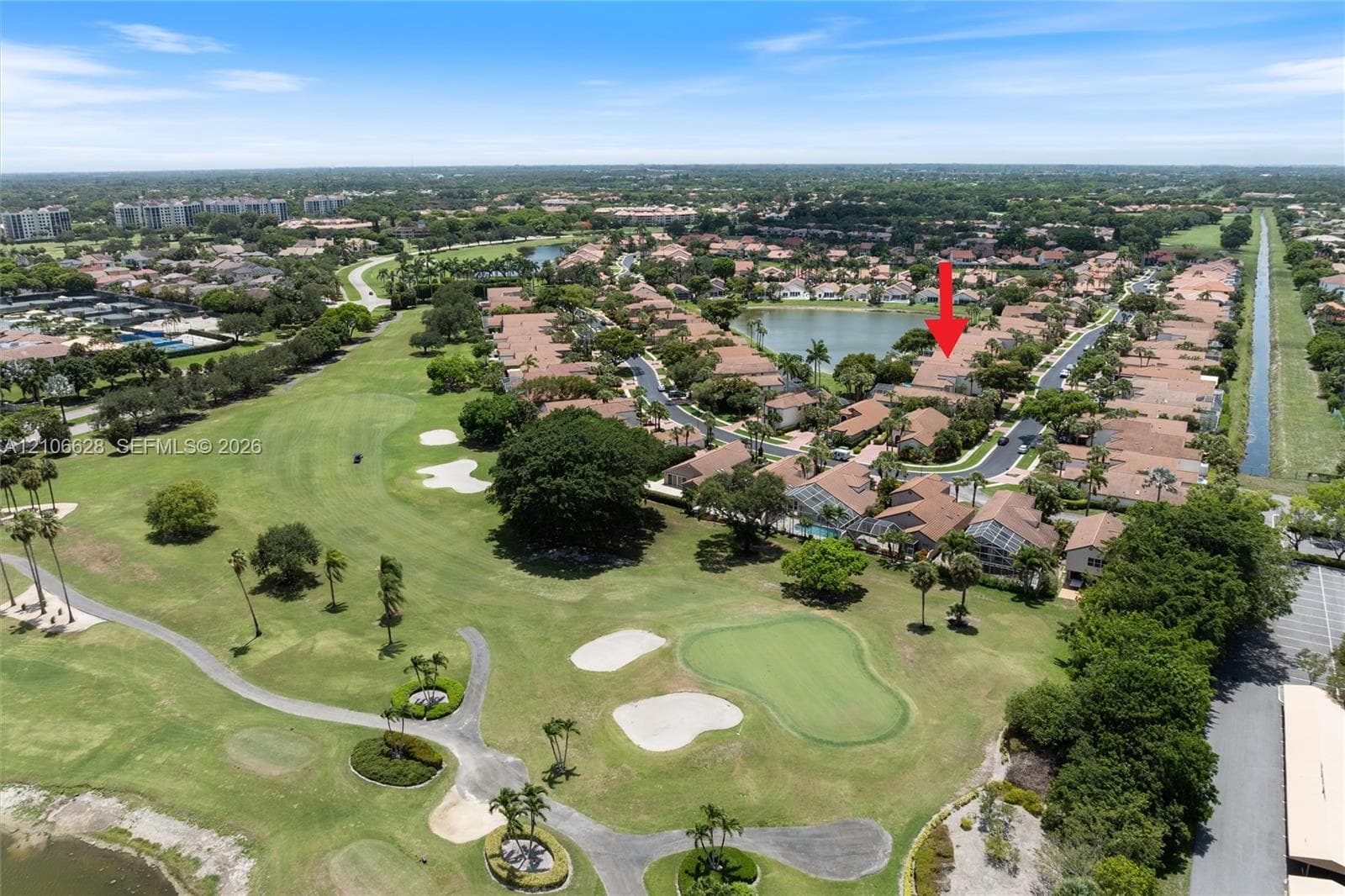 Aerial perspective of a residential property featuring proximity to an expansive golf course, mature landscaping, and a nearby lake