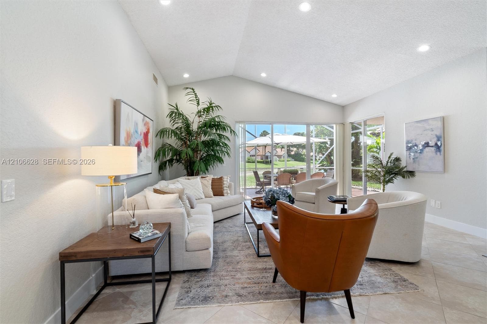 Vaulted ceilings with recessed lighting, tile flooring, and oversized glass sliding doors opening to a screened outdoor area