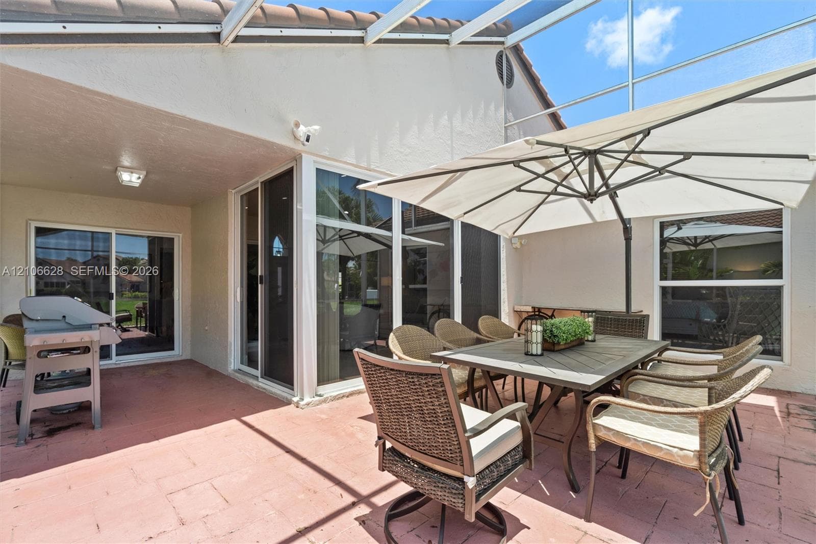 Screen-enclosed patio featuring masonry tile flooring, sliding glass door access, and a covered lanai area