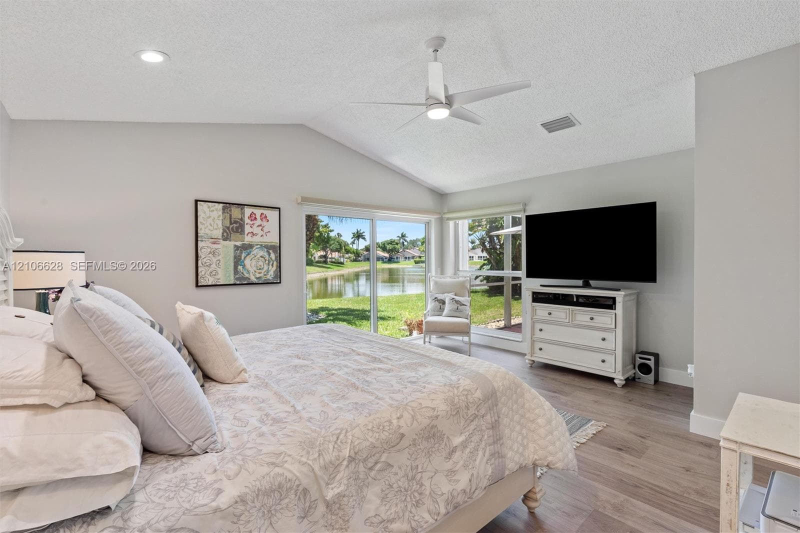 Vaulted ceiling with integrated lighting, wood-finish flooring, and expansive sliding glass doors opening to a water feature