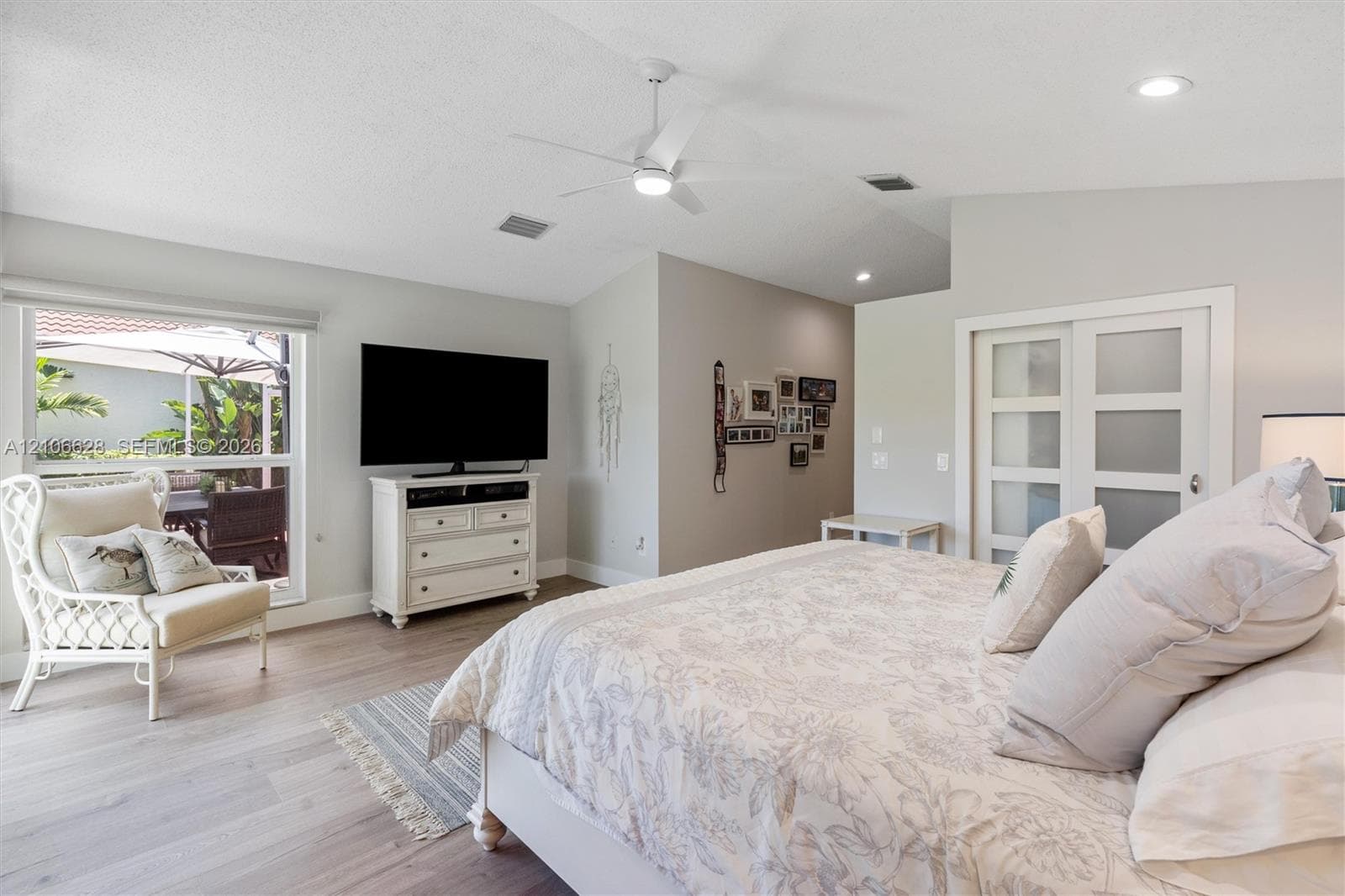 Vaulted ceilings with a central fan, wood-finish flooring, and frosted-glass panel doors