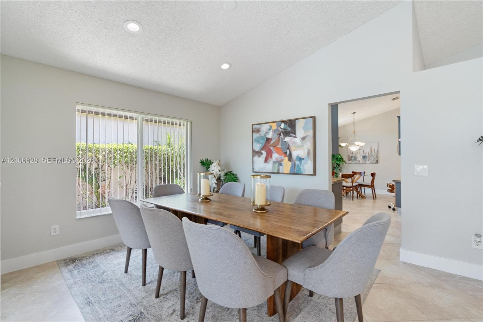 Vaulted ceilings, large window with vertical blinds, recessed lighting, and tile flooring