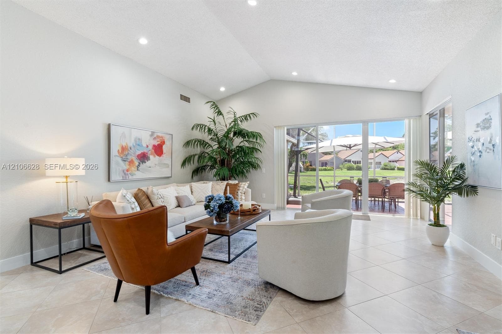 Vaulted ceilings, neutral ceramic tile flooring, recessed lighting, and large sliding glass doors providing access to a screened patio