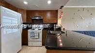 Kitchen featuring wood cabinetry, black countertops, a breakfast bar, recessed lighting, and pendant lighting