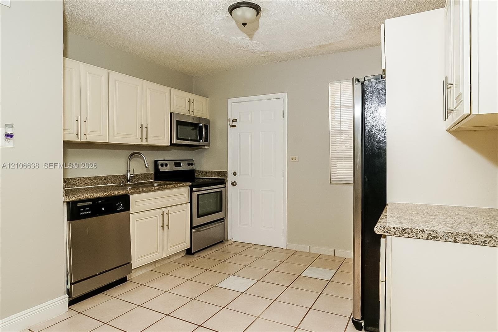 Kitchen featuring off-white cabinetry, stone-finish countertops, stainless steel appliances, and ceramic tile flooring