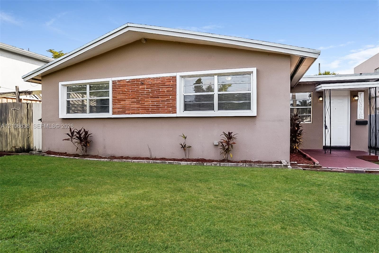 Mid-century modern architectural profile featuring a low-pitched gabled roof, horizontal siding, masonry accent paneling, and a covered front entryway with wrought-iron support columns