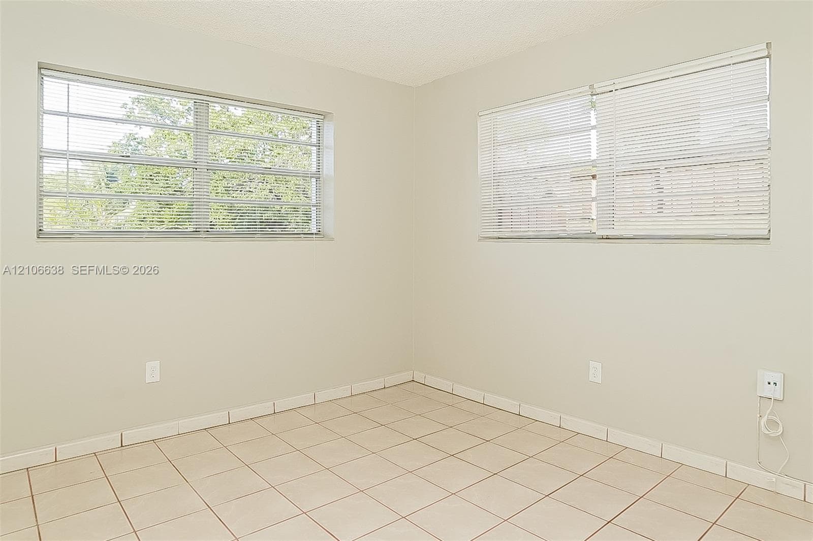 Neutral-toned interior space featuring large multi-pane windows and light-colored ceramic tile flooring
