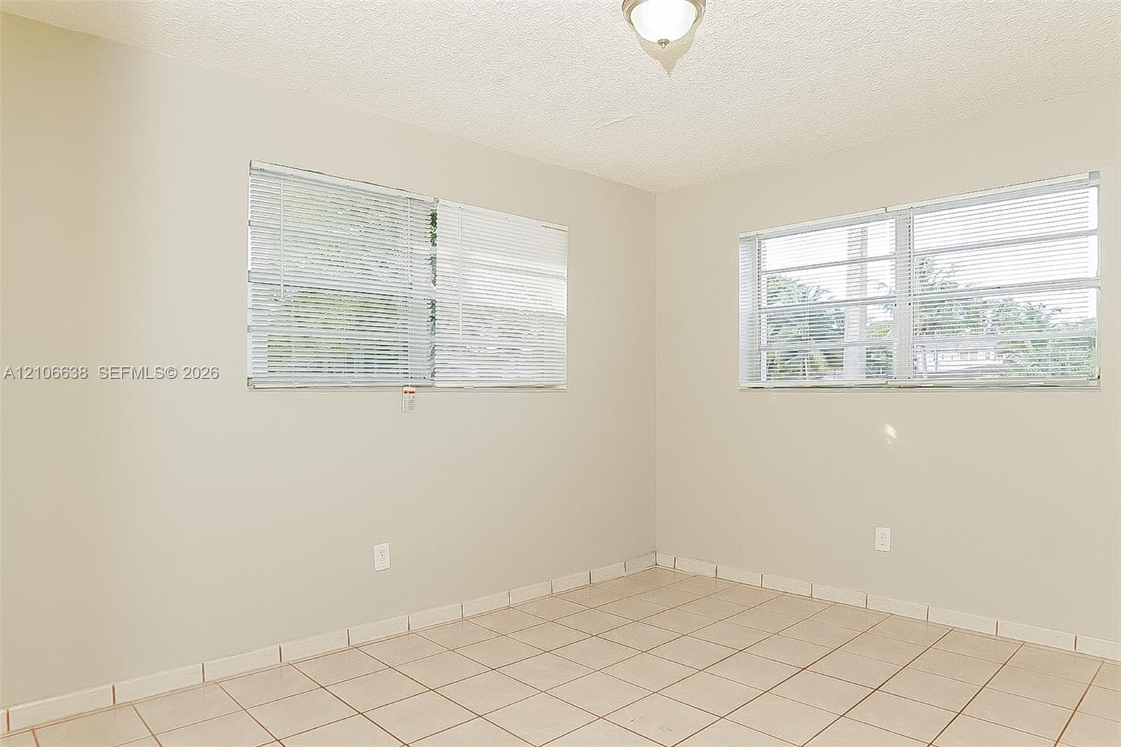 Neutral-toned interior featuring ceramic tile flooring, dual louvered-style windows, and a central ceiling-mounted light fixture