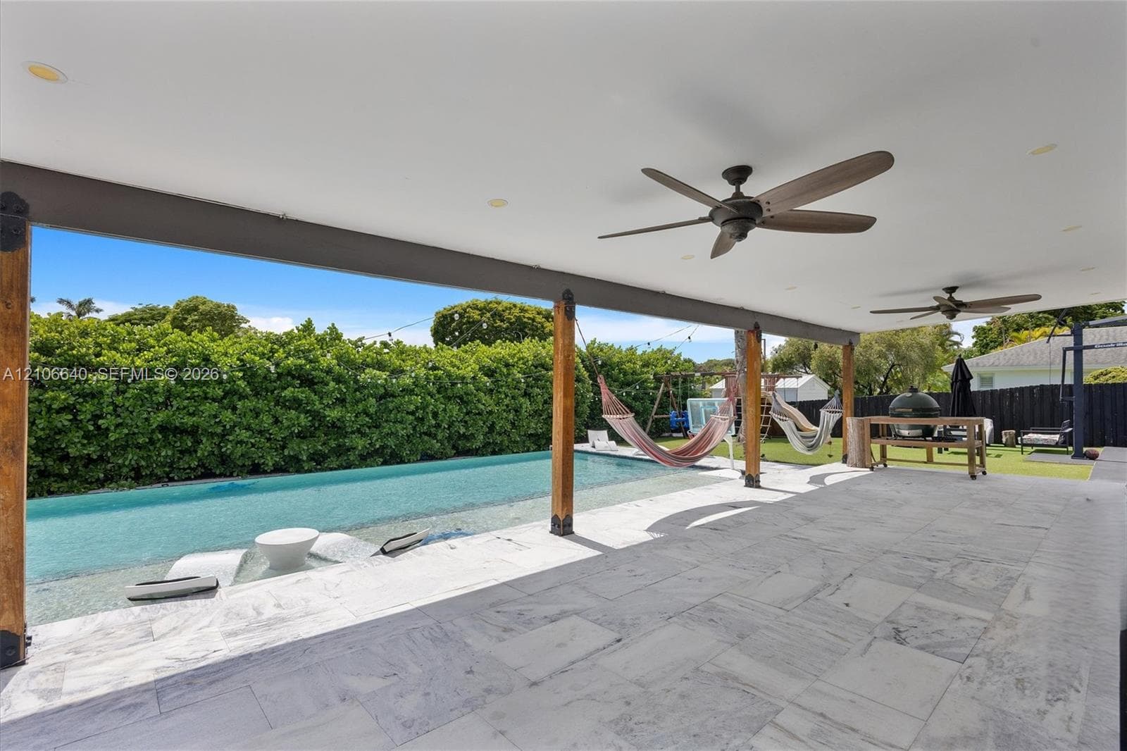 Covered patio featuring a swimming pool, multiple ceiling fans, and a tiled surface