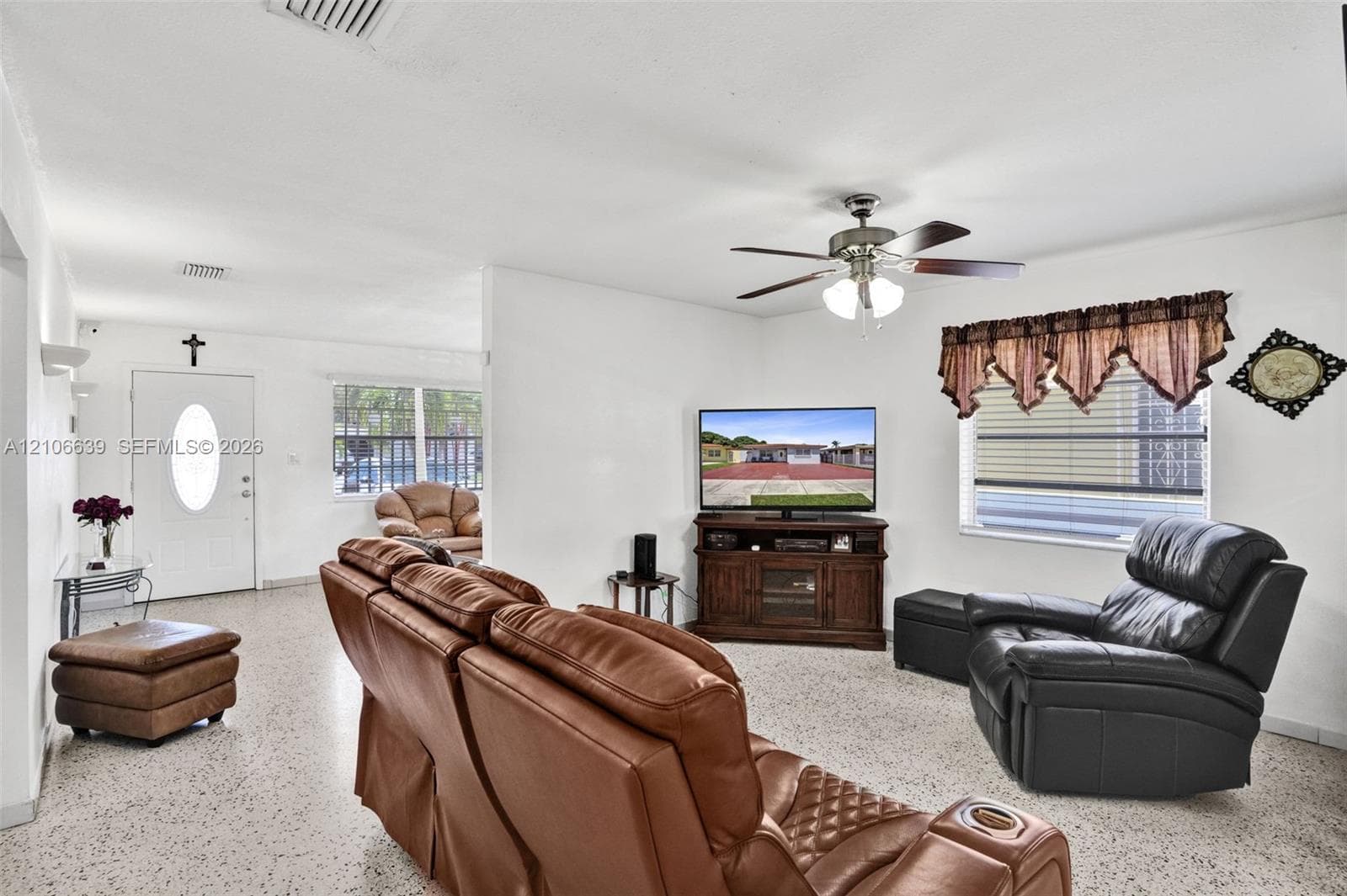 Living area featuring speckled stone-finish flooring, a ceiling fan with integrated lighting, and horizontal sliding windows