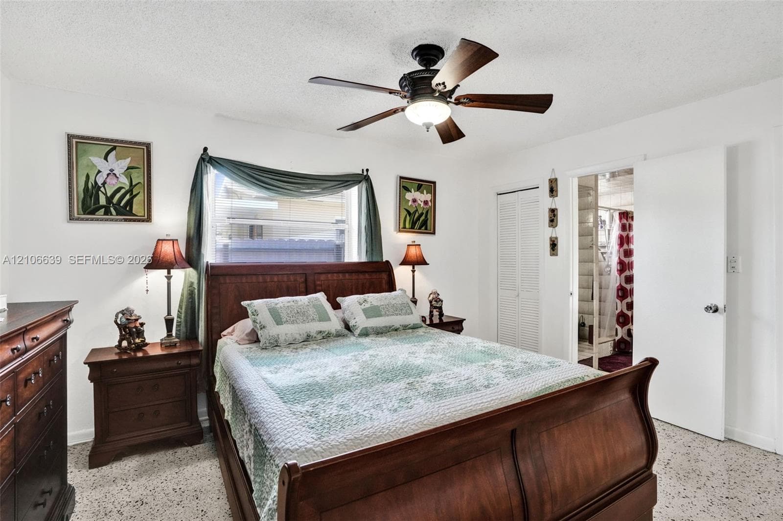 Bedroom featuring terrazzo flooring, white walls, louvered closet doors, and a ceiling fan with integrated lighting
