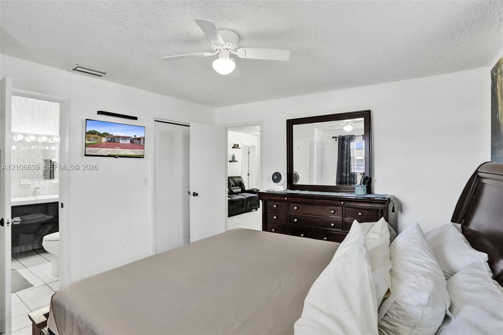 Room featuring a white ceiling fan with integrated light fixture, textured ceiling, and louvered closet doors