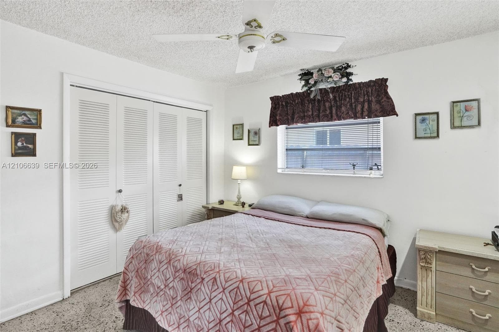 Bedroom featuring a ceiling fan with integrated lighting, dual louvered closet doors, and window with horizontal blinds