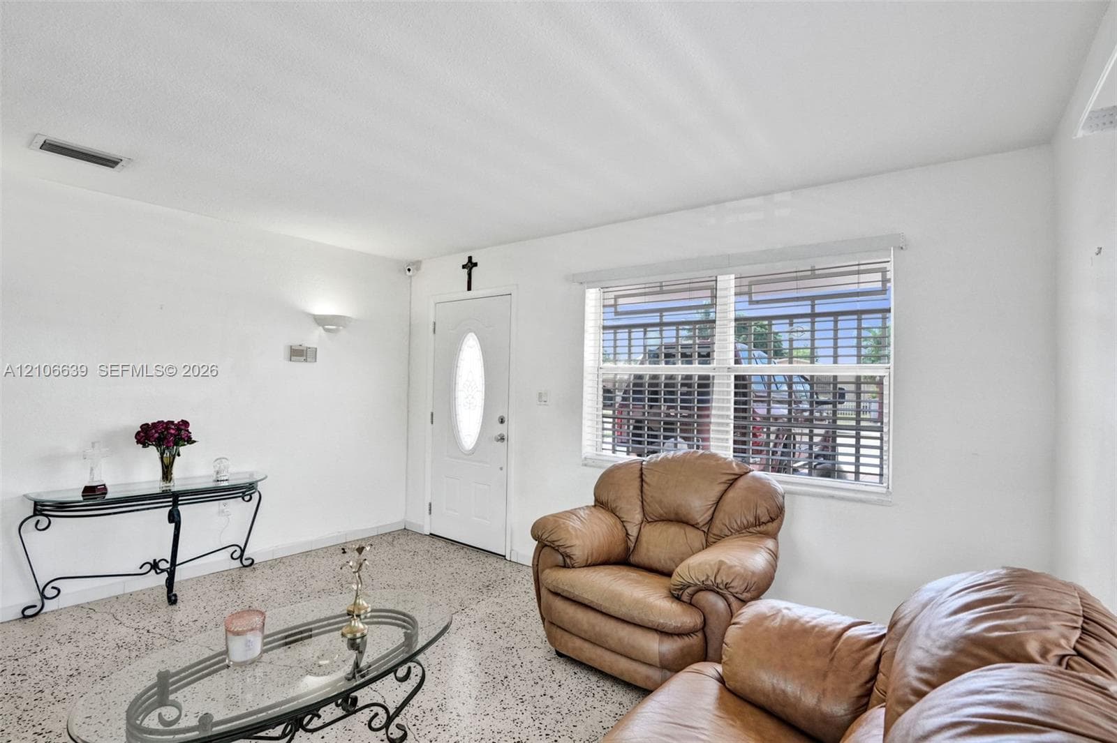 Living space featuring terrazzo flooring, white walls, and a recessed-panel entry door with an oval glass insert