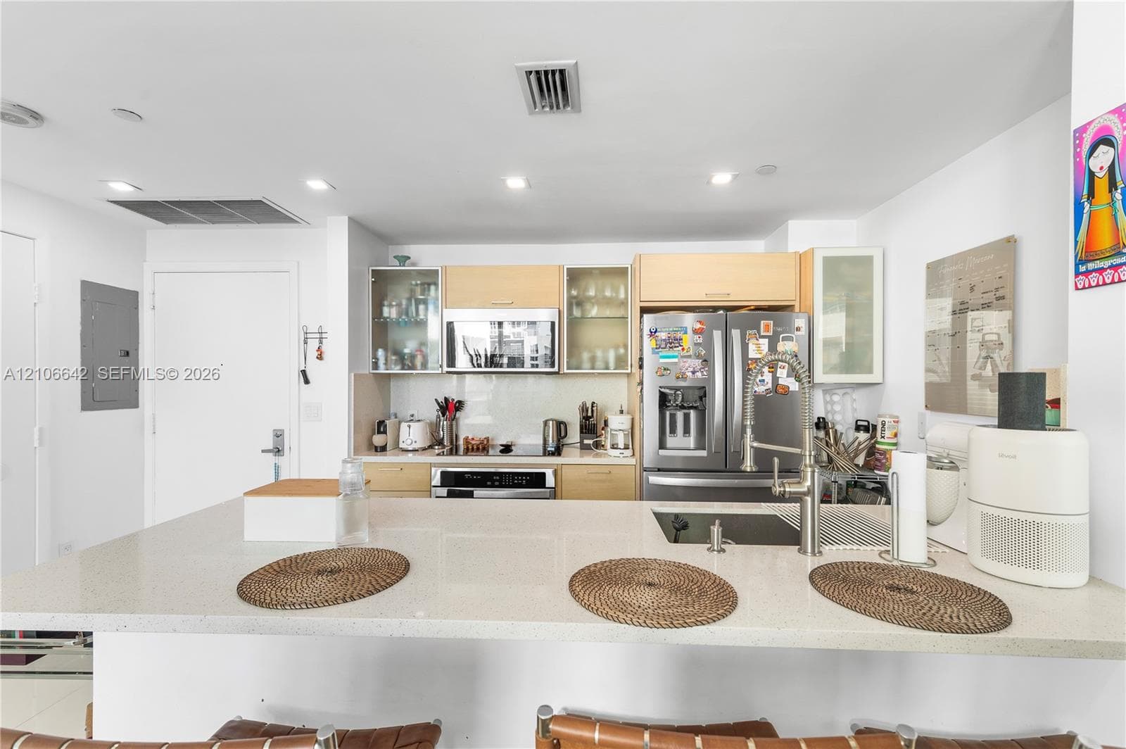 Kitchen featuring light-finish cabinetry, stone-surface countertop with breakfast bar, stainless steel appliances, and high-arc pull-down faucet