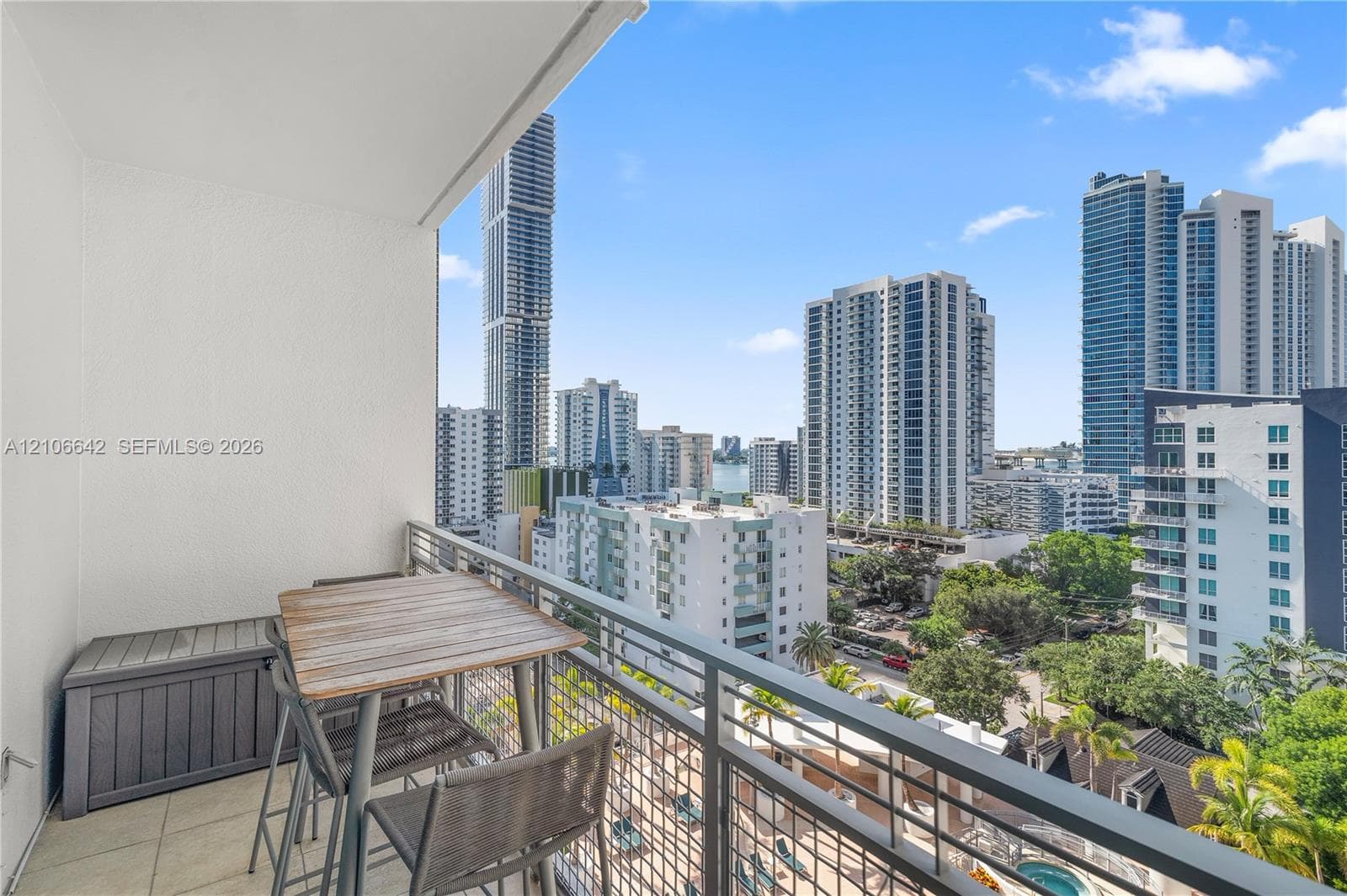 Covered private balcony featuring tile flooring and metal railings, overlooking an urban skyline