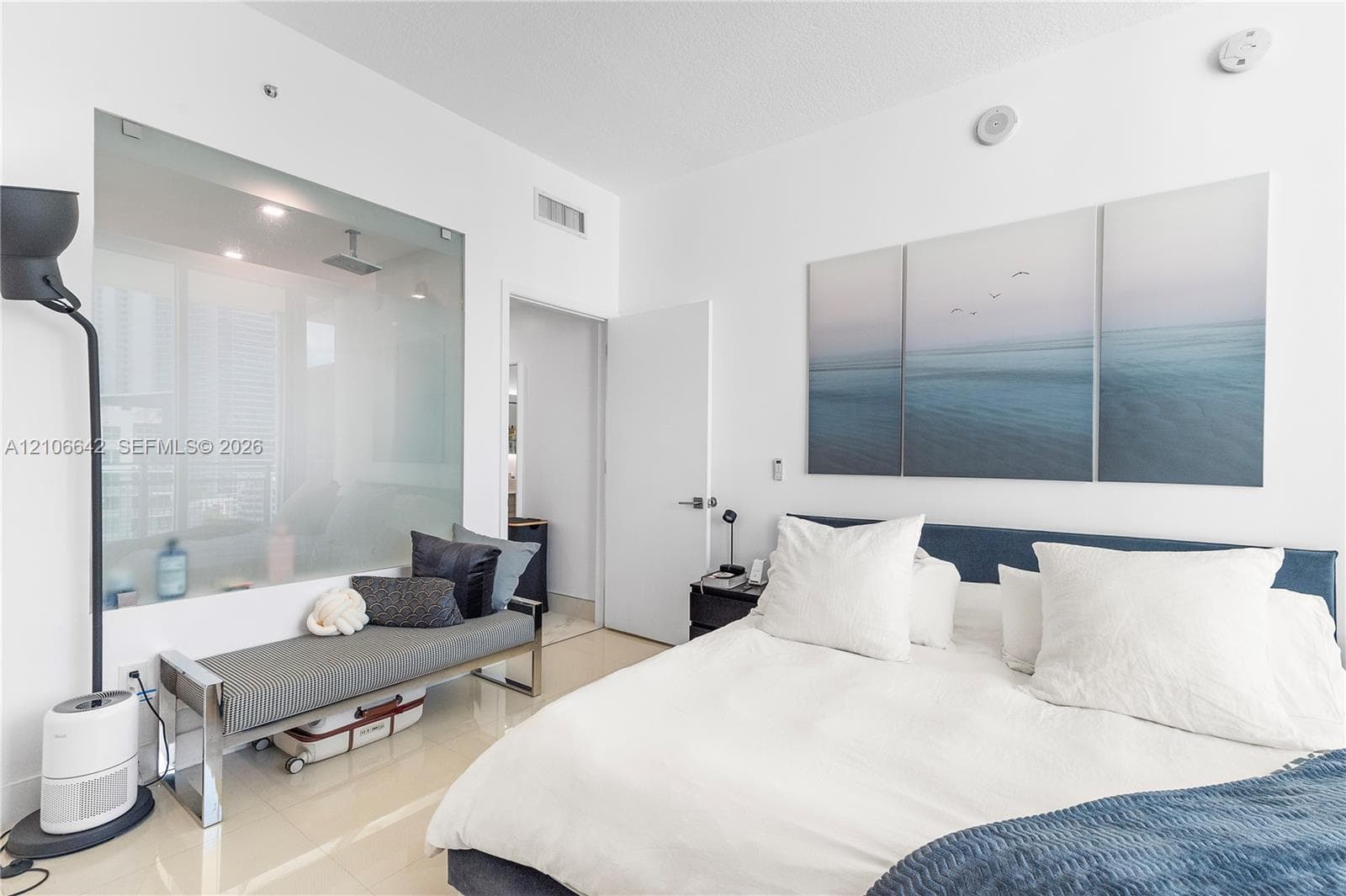 Room featuring polished tile flooring, a floor-to-ceiling glass wall panel, and smooth, neutral-toned wall surfaces