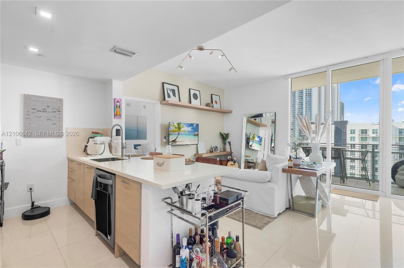 Open-concept kitchen and living area featuring quartz countertops, wood-finish cabinetry, recessed lighting, and floor-to-ceiling glass sliding doors leading to a private balcony