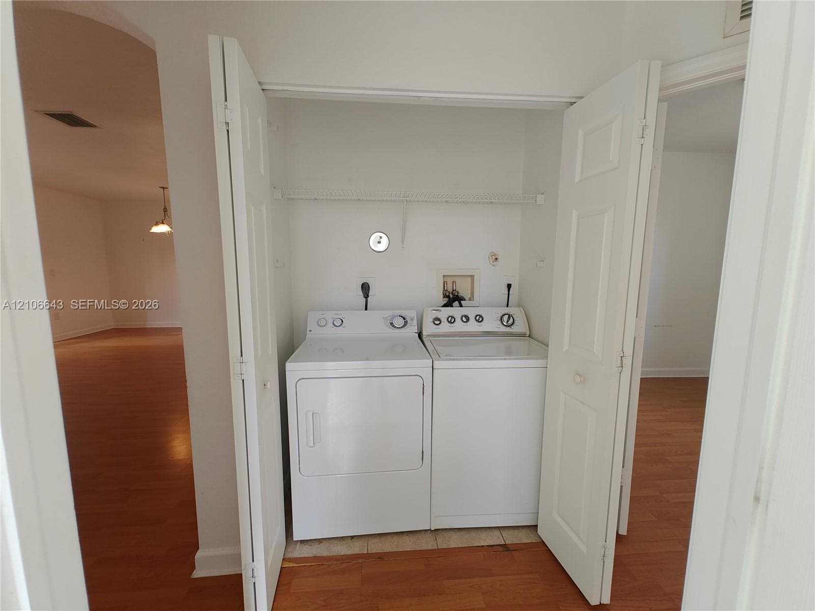 Laundry closet featuring bi-fold doors, white appliance hookups, and built-in wire shelving