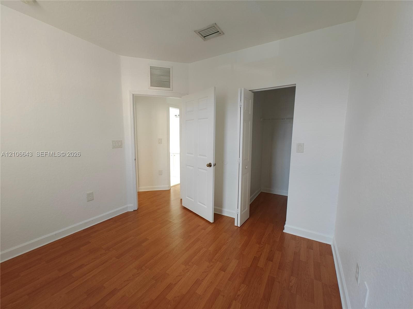 Room featuring wood-finish flooring, white walls, and a closet with bifold doors