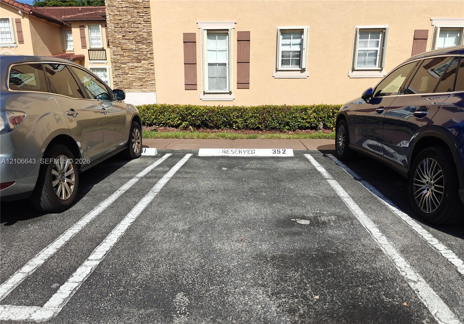 Assigned reserved parking space featuring asphalt paving, concrete wheel stops, and direct building access
