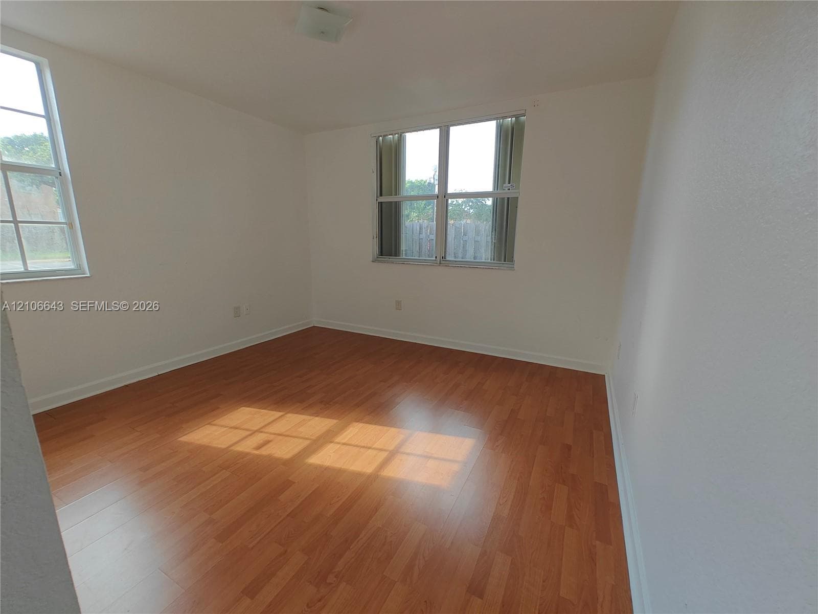 Room featuring wood-finish flooring, neutral walls, and multiple grid-pattern windows