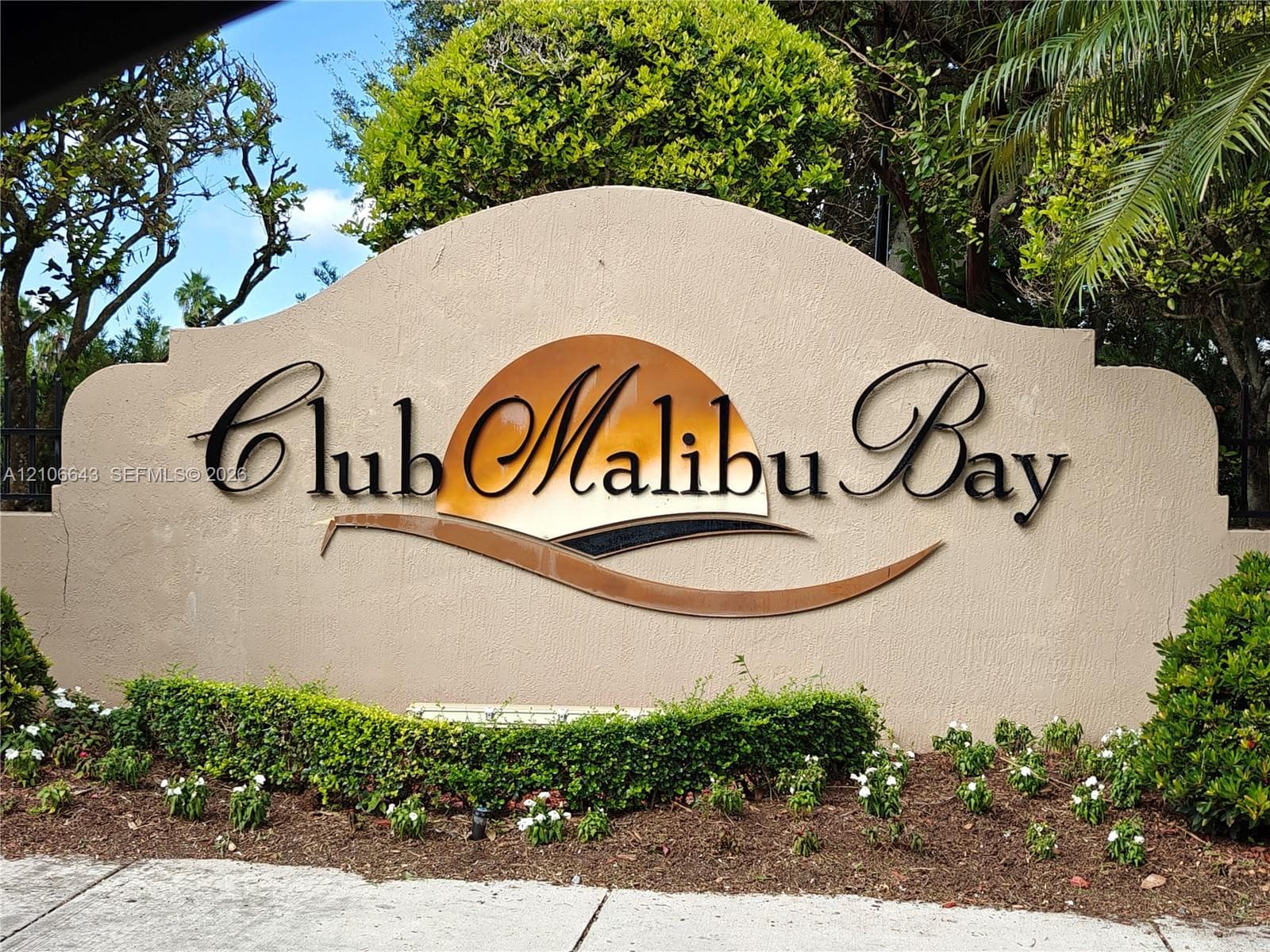 Stucco monument signage featuring dimensional metal lettering, a metallic graphic accent, and professionally manicured landscaping