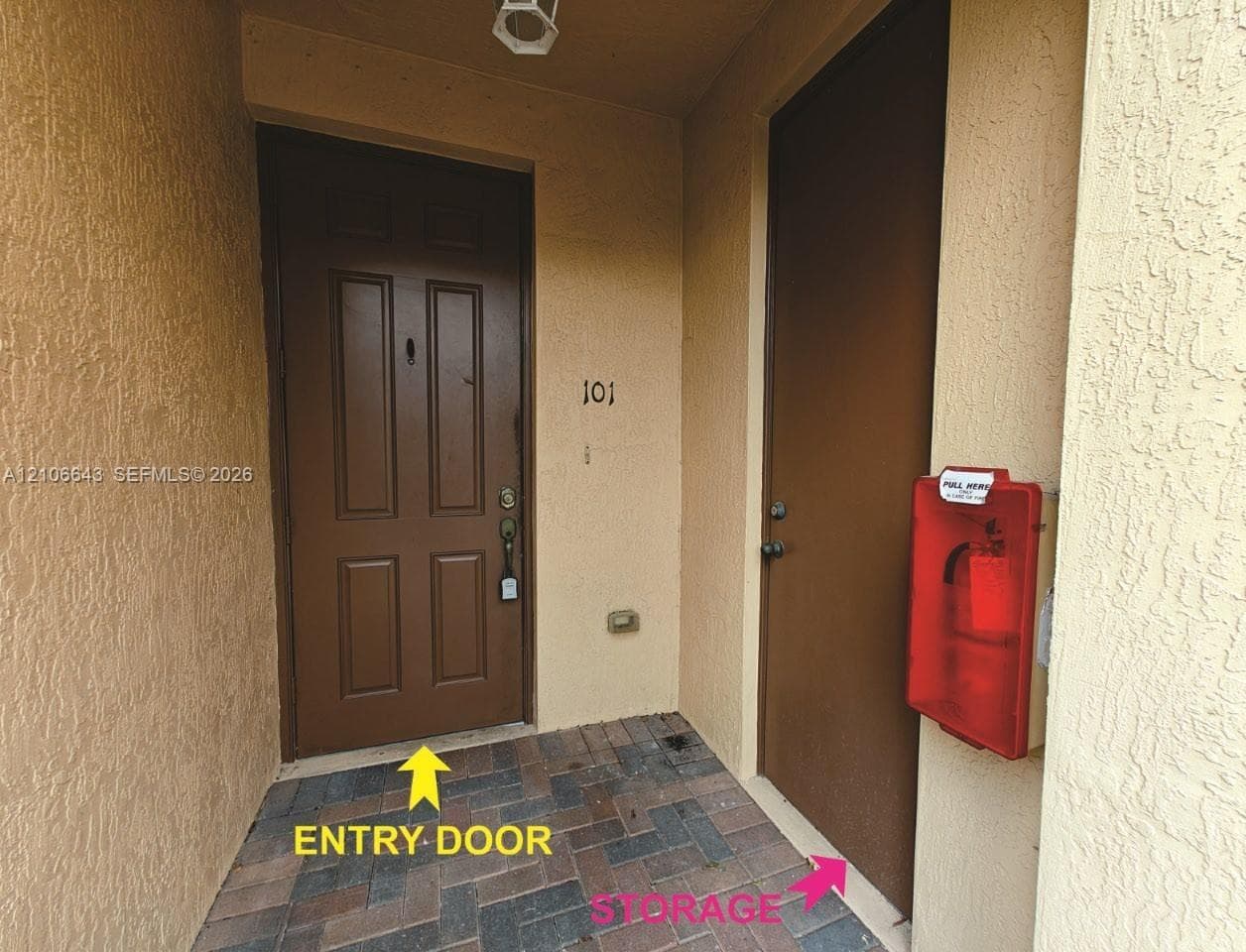 Covered entryway featuring paver flooring, solid-panel entry door, and dedicated storage closet