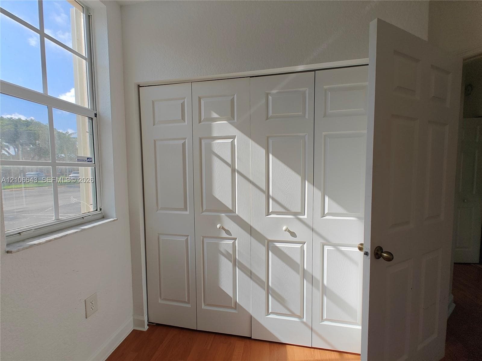 Multi-panel window with a stone sill, four-panel folding closet doors, and wood-finish flooring
