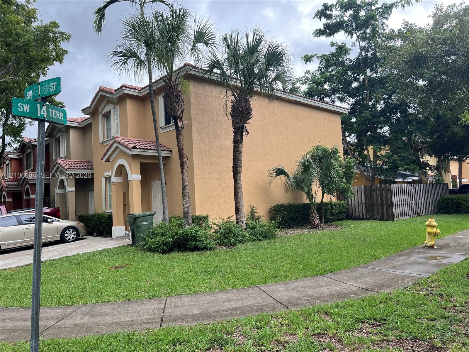 Two-story stucco exterior featuring a clay tile roof, covered entryway, and concrete driveway