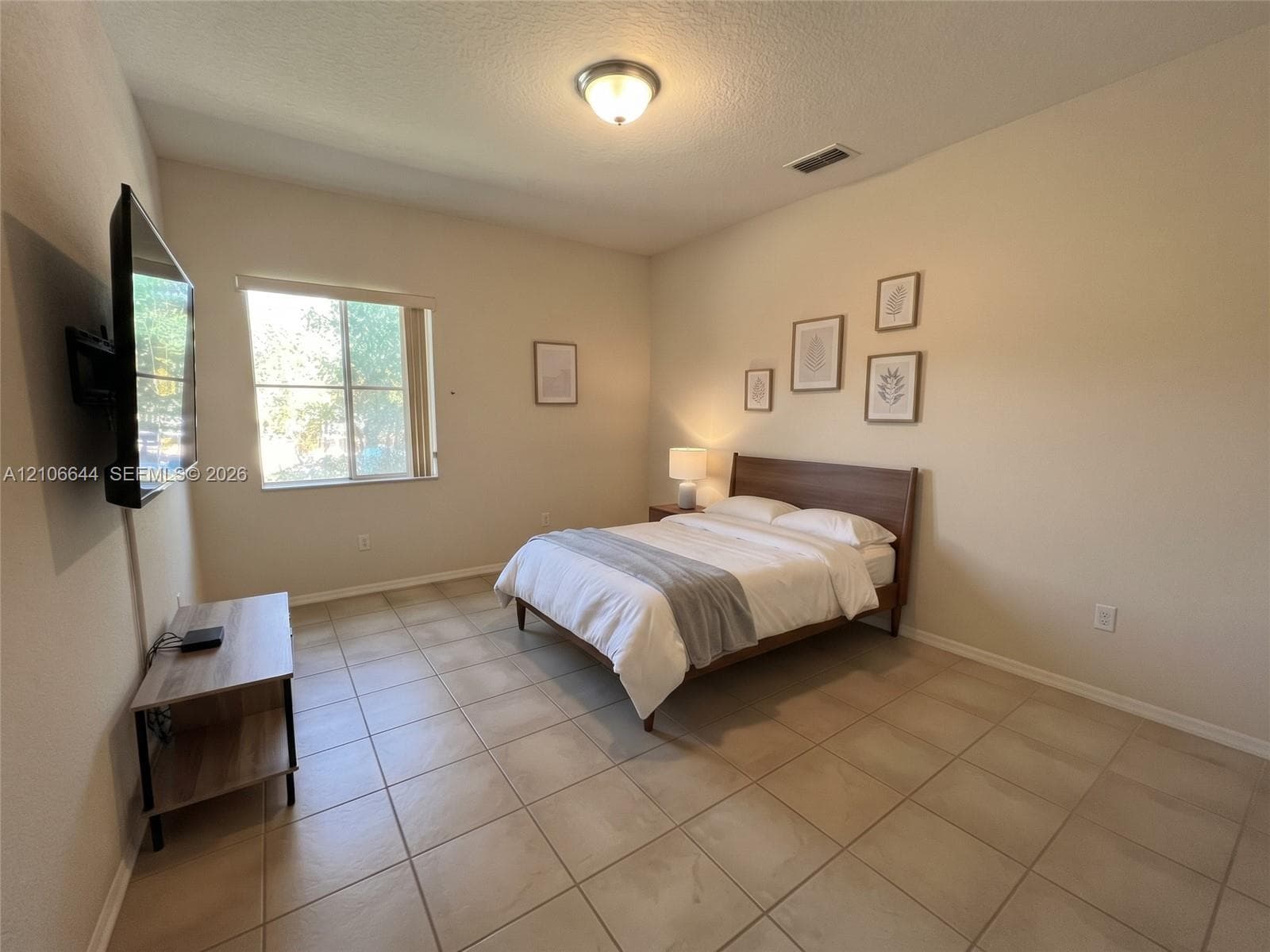 Neutral-toned room featuring large-format ceramic tile flooring, a dual-pane window, and a flush-mount ceiling light fixture