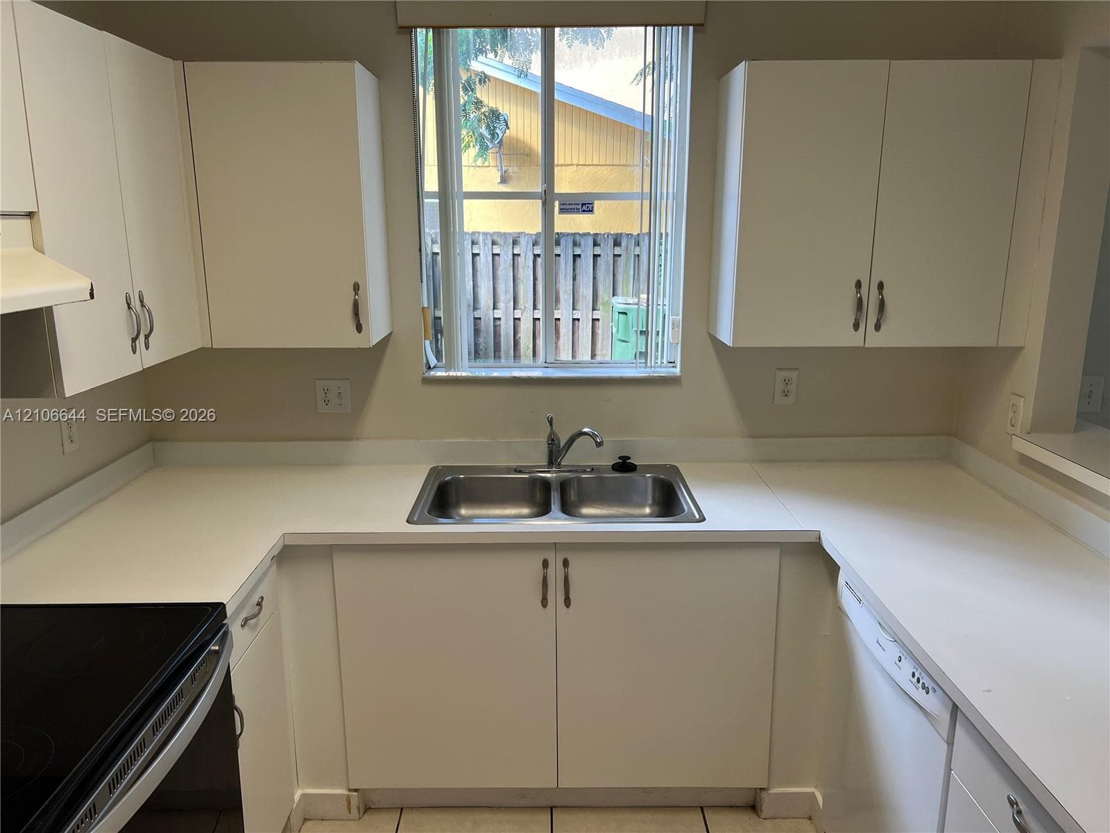 Kitchen featuring white cabinetry, solid-surface countertops, a double-basin stainless steel sink with a gooseneck faucet, and a built-in dishwasher