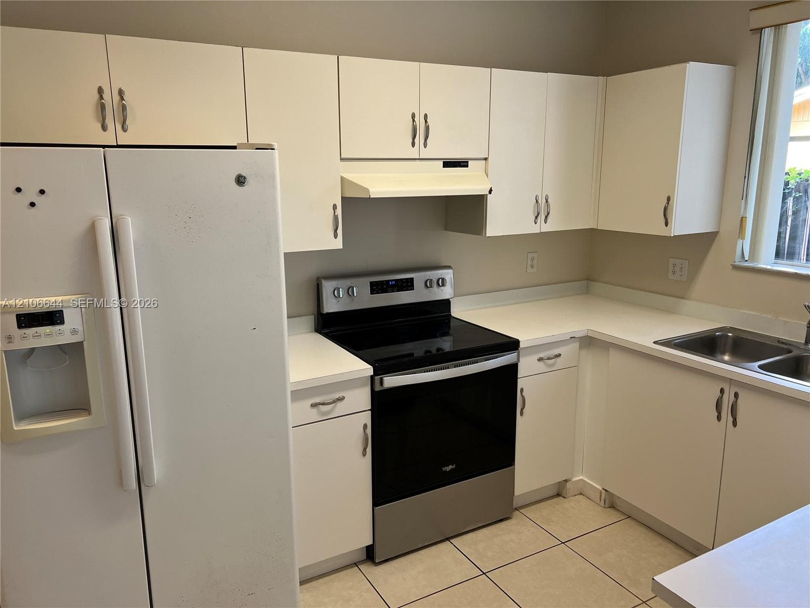 Kitchen featuring white cabinetry, solid-surface countertops, dual-basin stainless steel sink, and stainless steel freestanding range