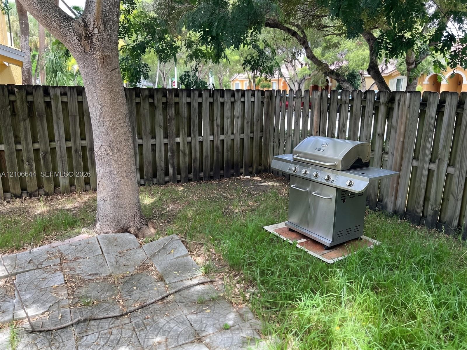 Private backyard featuring a wood privacy fence, concrete paver patio, and mature trees