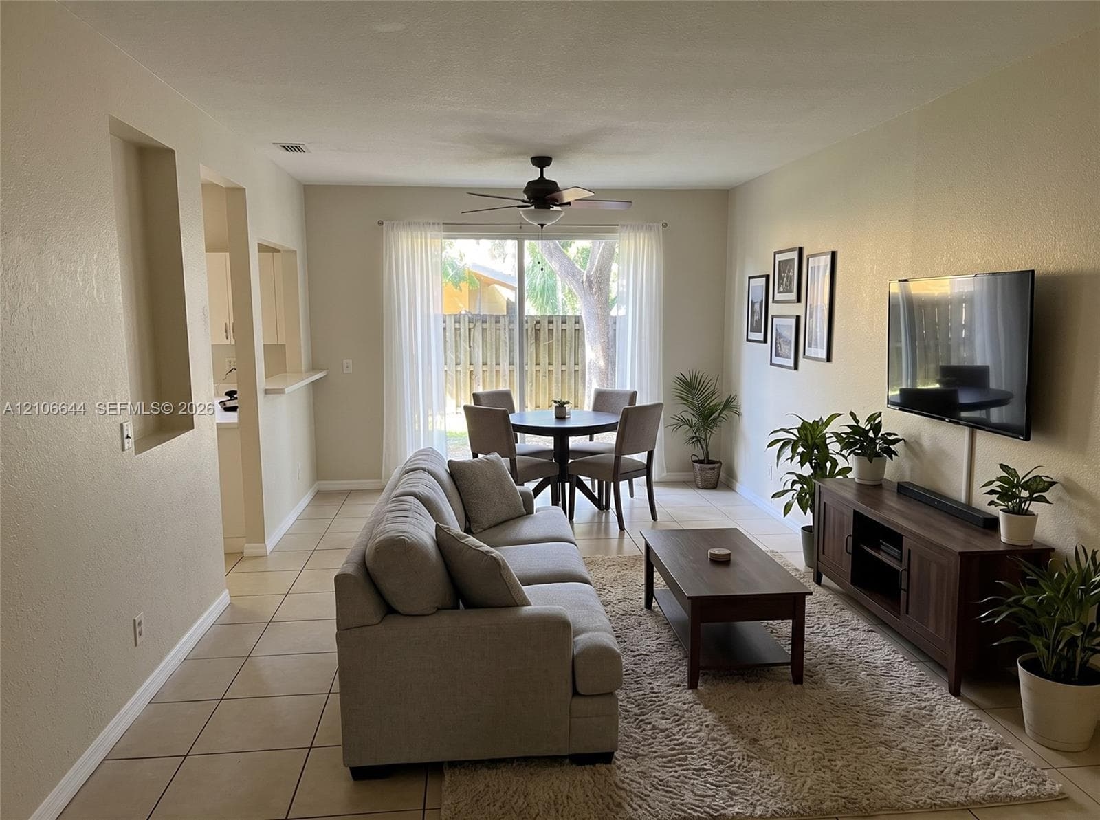 Living area featuring ceramic tile flooring, a recessed wall niche, a ceiling fan, and sliding glass doors leading to the exterior