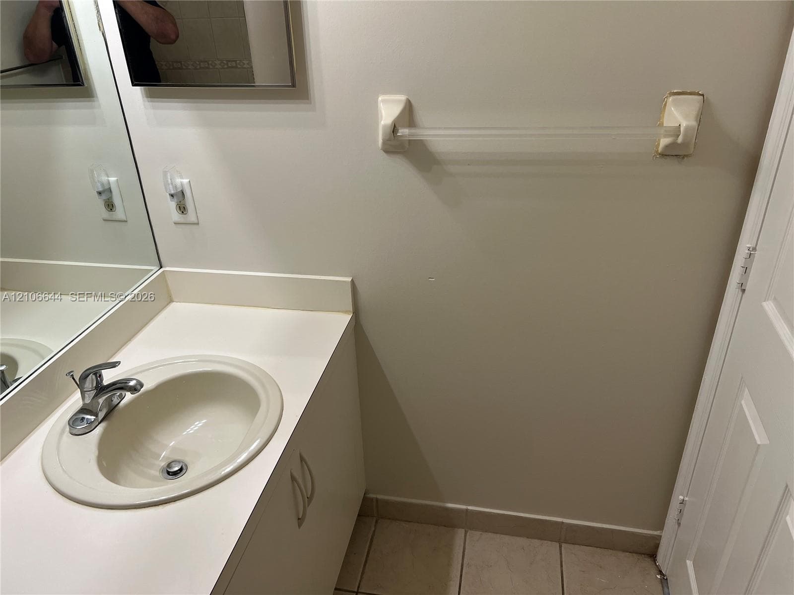 Bathroom vanity with a solid-surface integrated sink, chrome-finish faucet, built-in lower cabinetry, wall-mounted mirror, and tile flooring