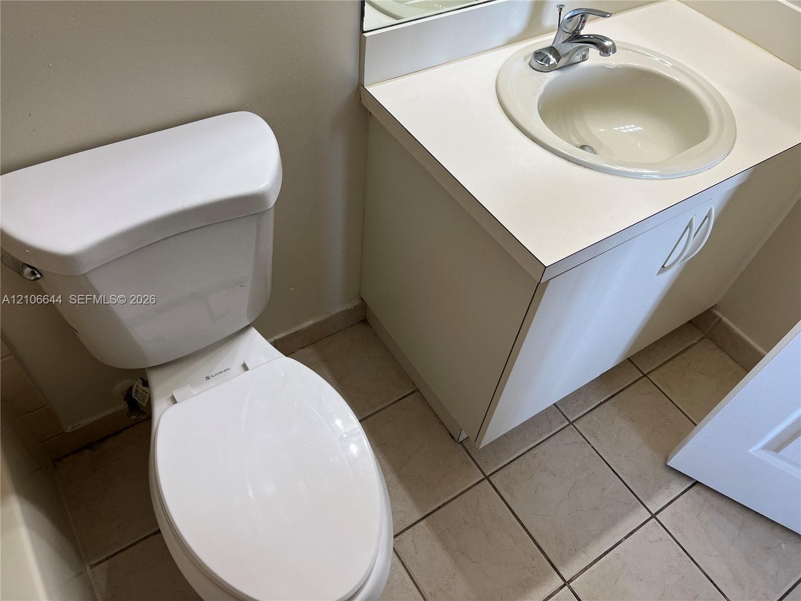 Bathroom featuring a vanity with an integrated sink and chrome faucet, solid-surface countertop, and ceramic tile flooring