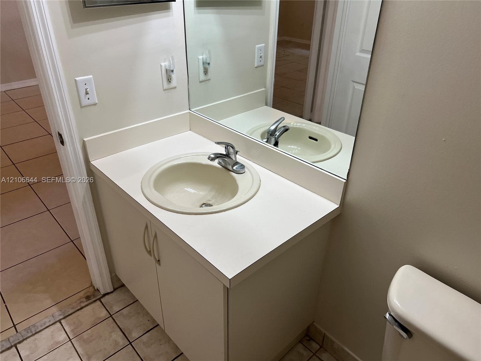 Vanity featuring a solid-surface countertop with an integrated basin, chrome-finish faucet, built-in lower cabinetry, and a large wall-mounted mirror