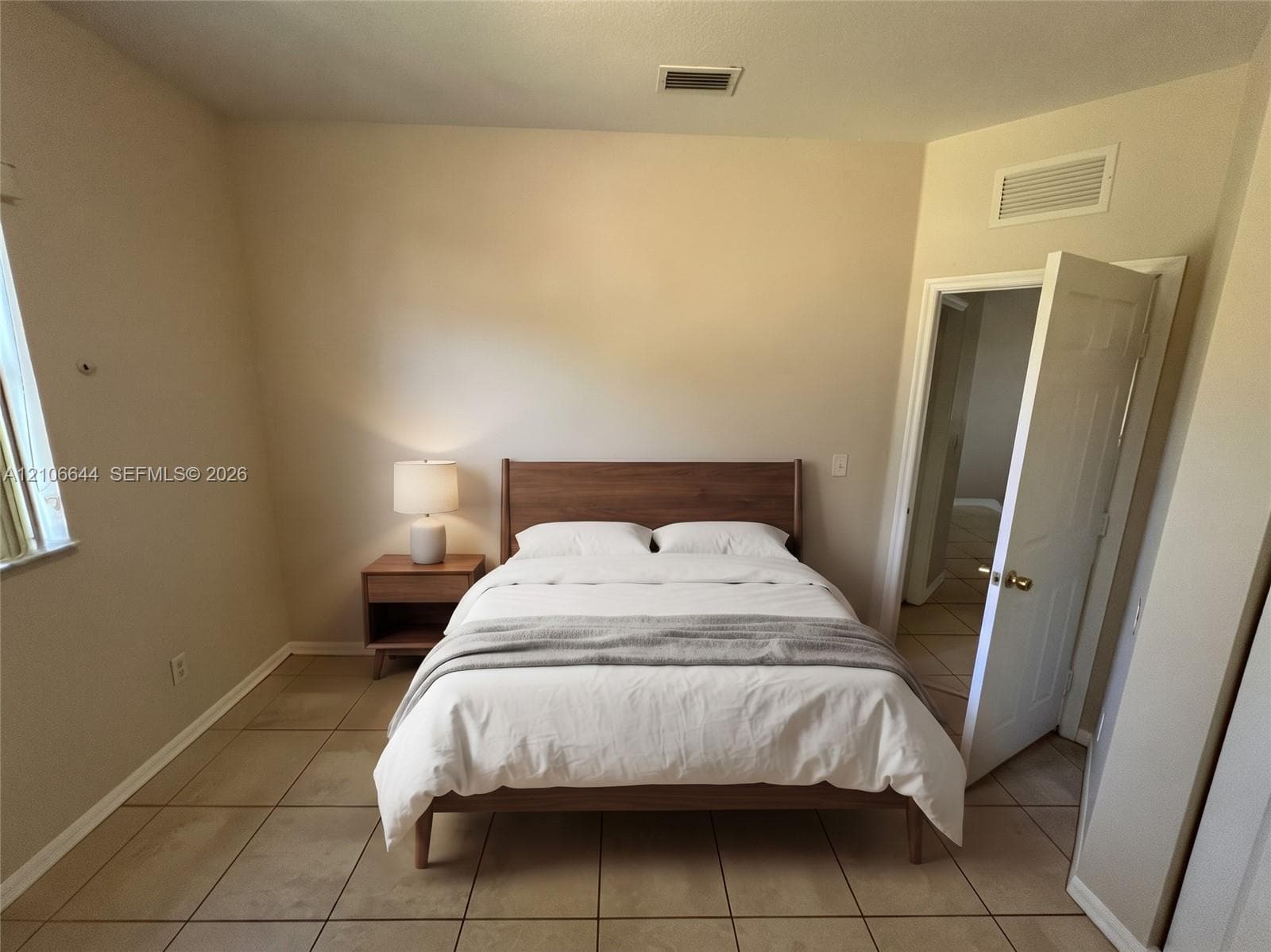 Neutral-toned room featuring large-format ceramic tile flooring, a window with natural lighting, and a six-panel interior door