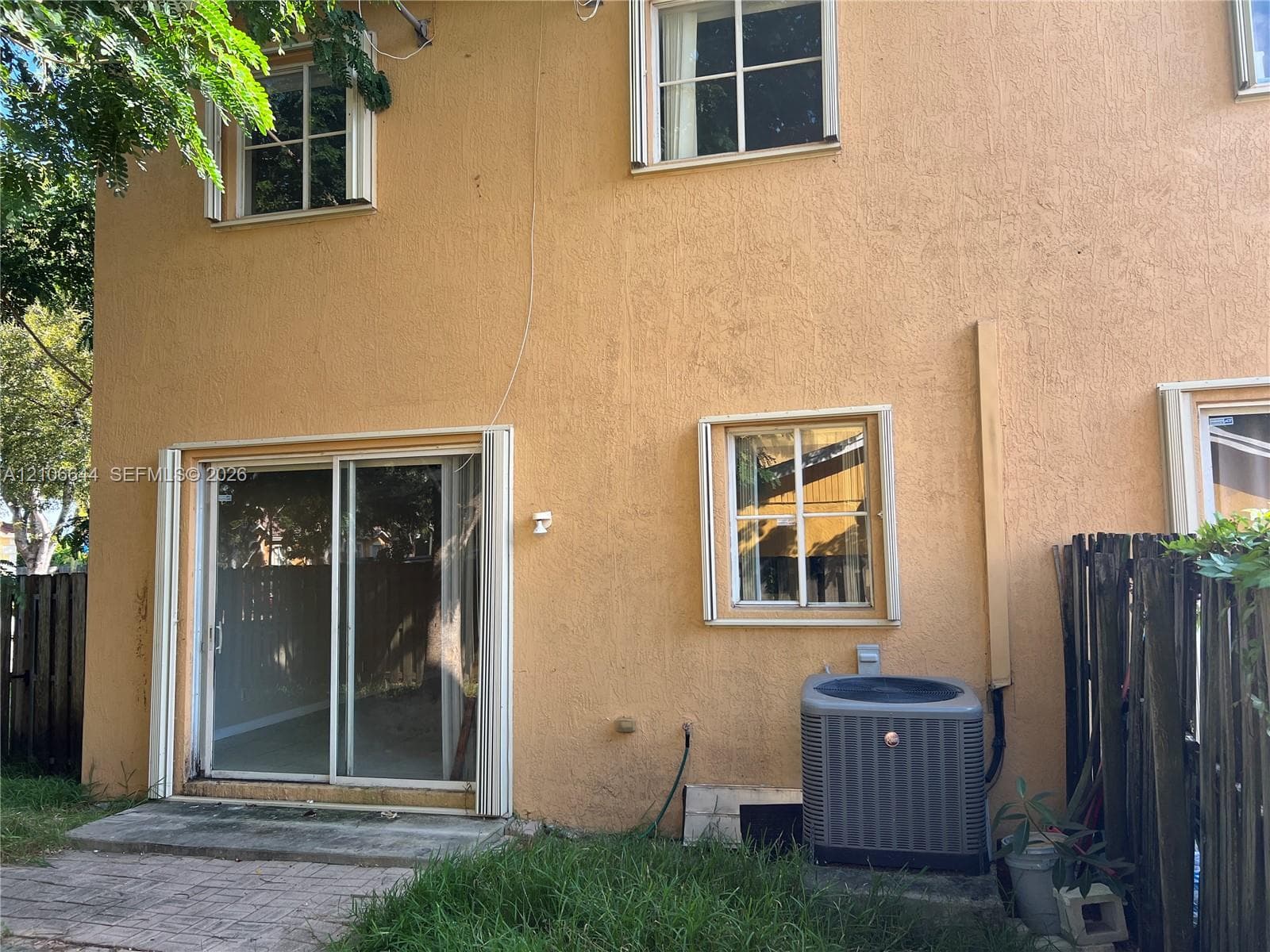 Stucco exterior featuring multi-pane windows, a sliding glass door, and an exterior HVAC unit
