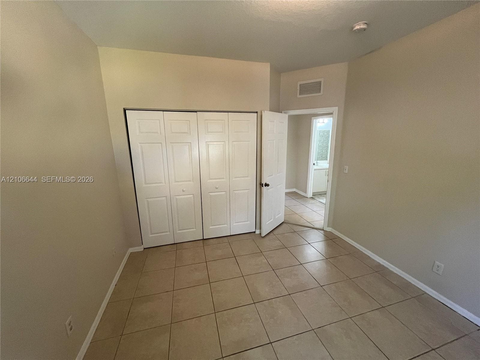 Interior space featuring neutral wall paint, tile flooring, and a multi-panel closet with white doors