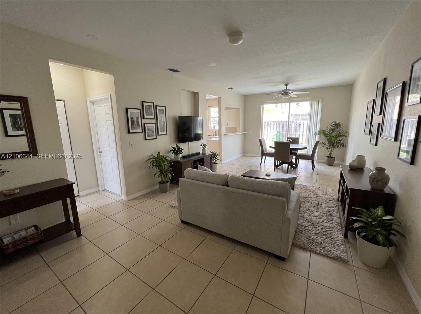 Open-concept living space featuring large-format ceramic tile flooring, a recessed media niche, a ceiling fan, and sliding glass doors providing outdoor access