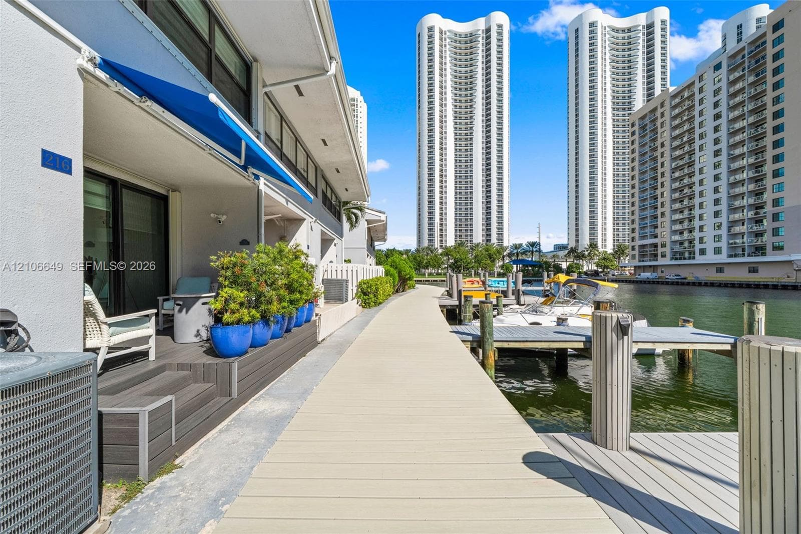 Waterfront residential complex featuring private boat slips, hardscaped docks, a multi-court tennis facility, and expansive coastal surroundings