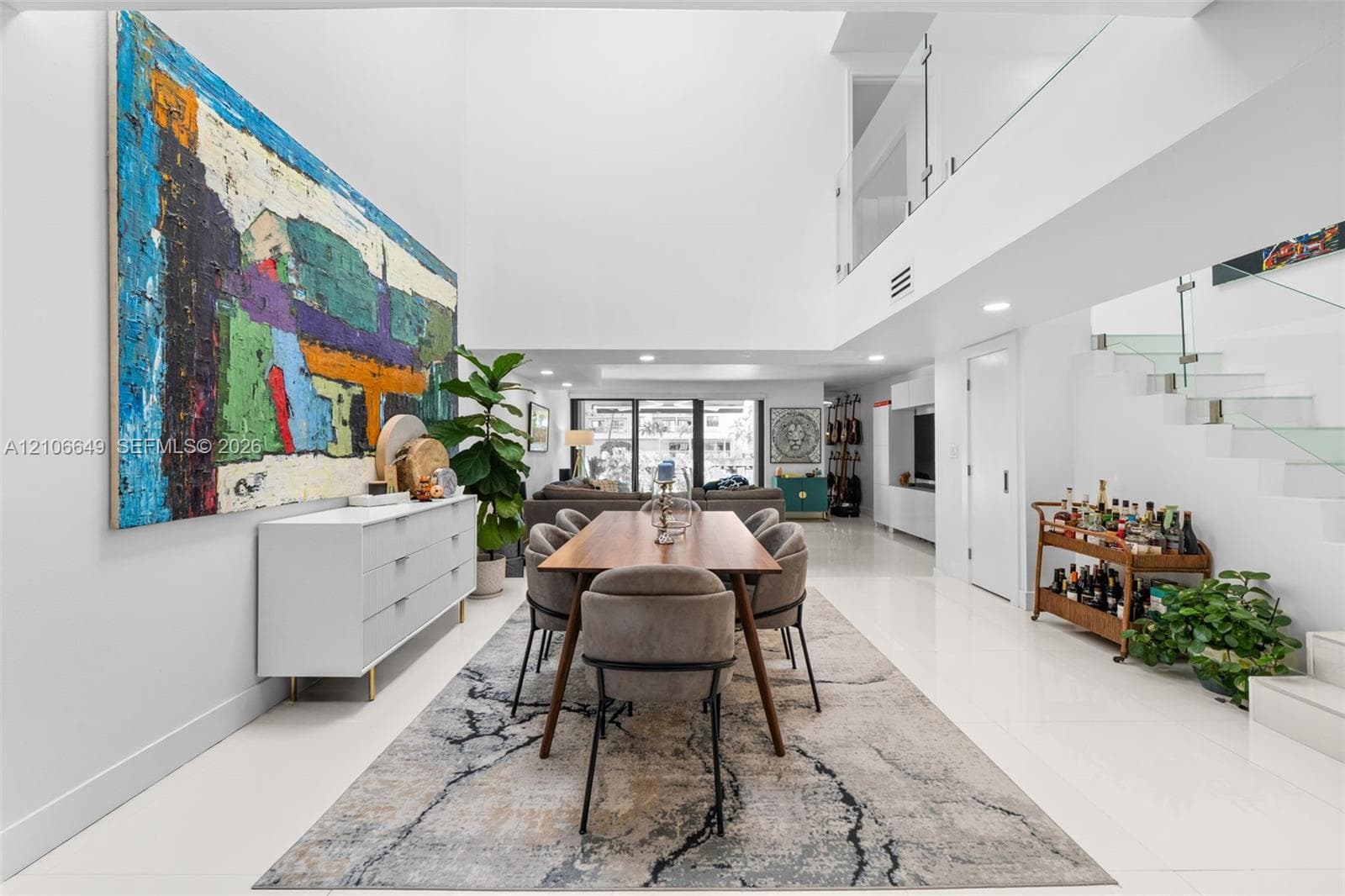 Double-height ceilings, polished tile flooring, floating staircase with glass railings, recessed lighting, and expansive wall space