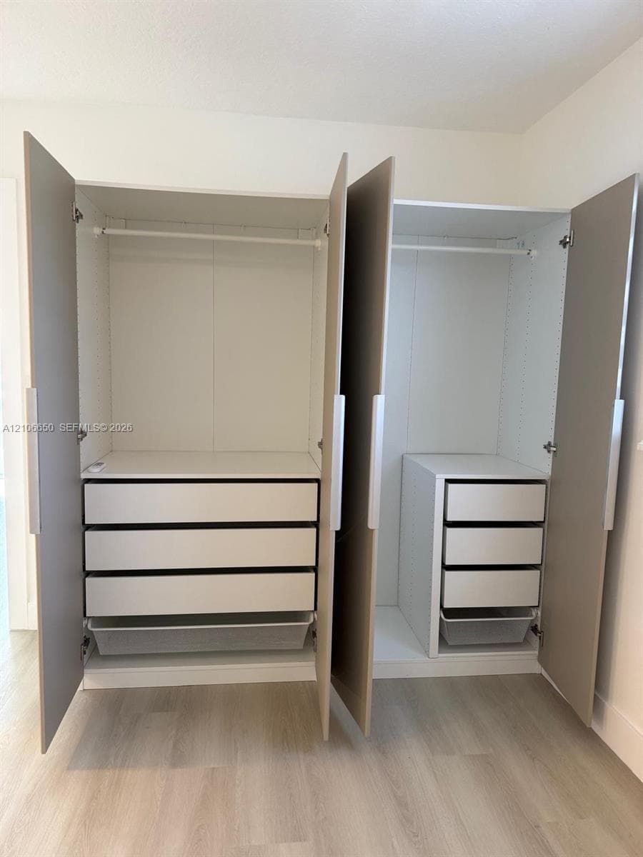 Custom-fitted closet system featuring light wood-finish doors, integrated white shelving, multiple drawers, and wire pull-out baskets