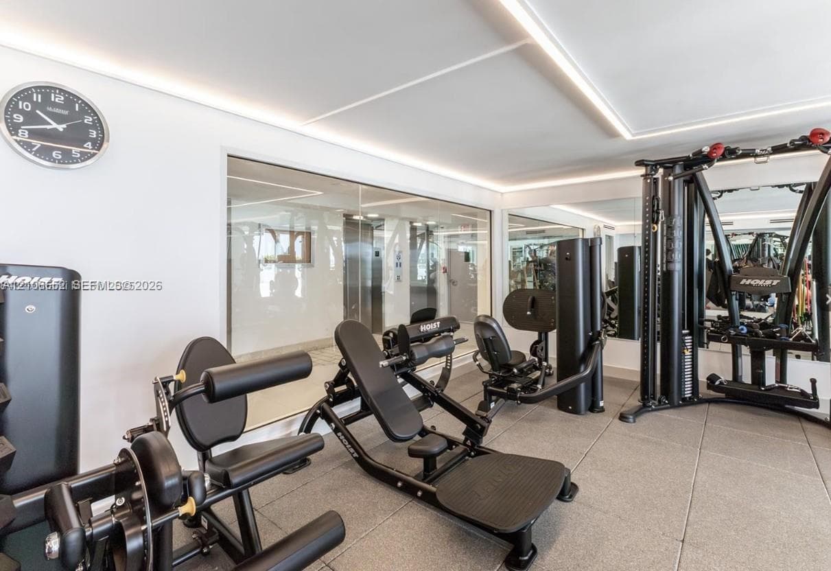 Fitness area featuring wall-to-wall mirrors, recessed linear lighting, and durable modular flooring