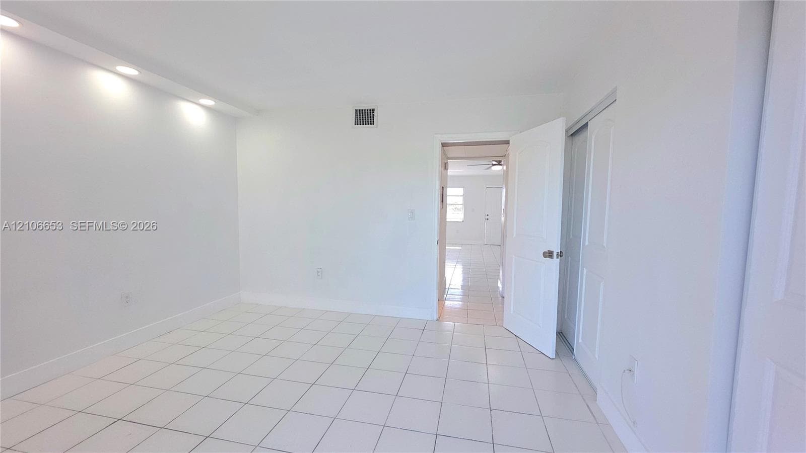 Neutral-toned interior featuring large-format ceramic tile flooring, recessed cove lighting, and a sliding-door closet with paneled detailing