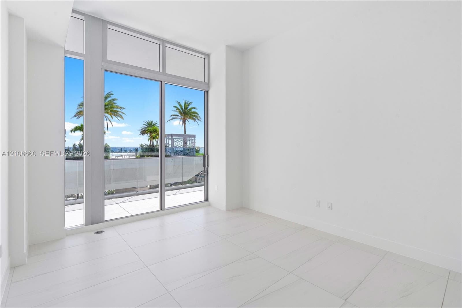 Floor-to-ceiling glass panel windows, large-format tile flooring, and integrated sliding glass door providing access to a balcony with a glass railing